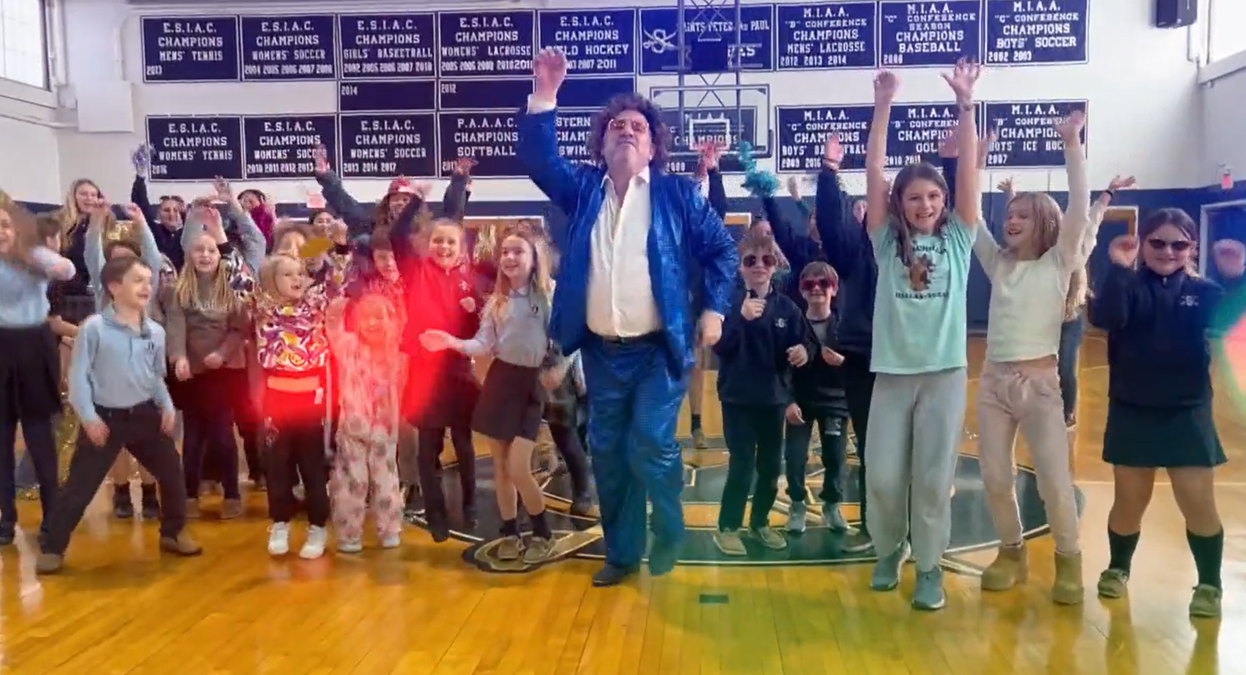 Father Nash dressed up in a disco suit with kids from SSPP school