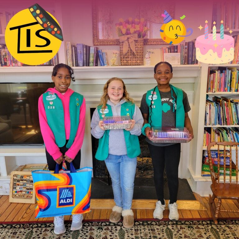 Girl scouts from Troop 528 holding birthday cake kits in the Easton's Promise living room