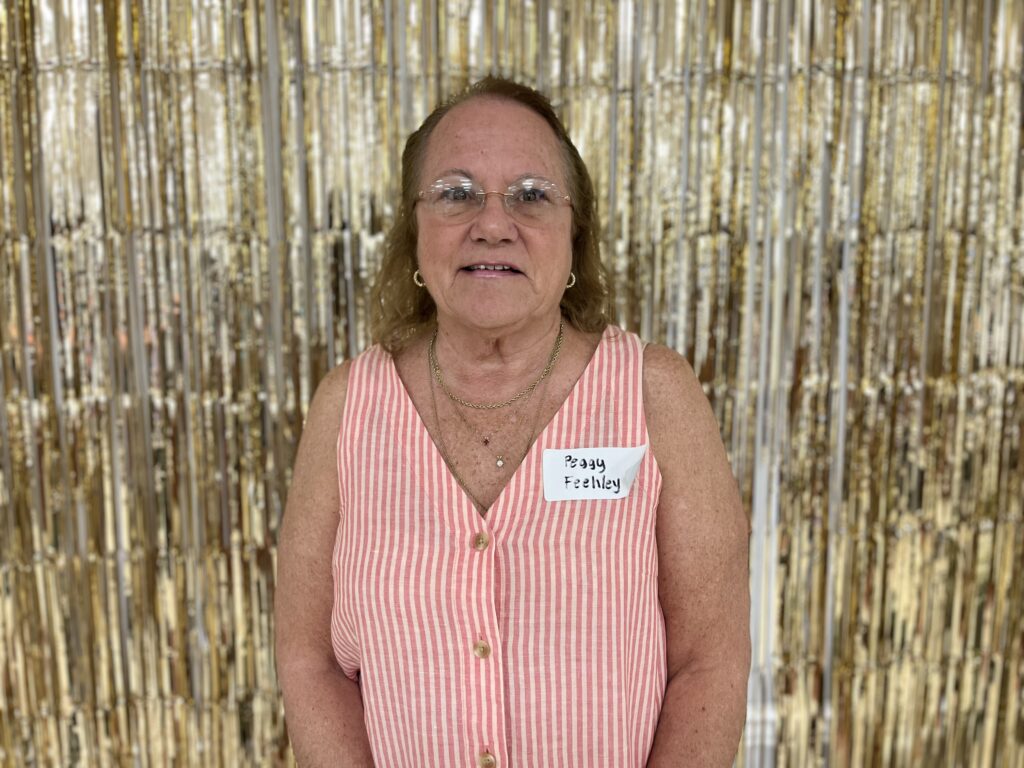 Photo of Peggy Feehley with a gold tinsel backdrop